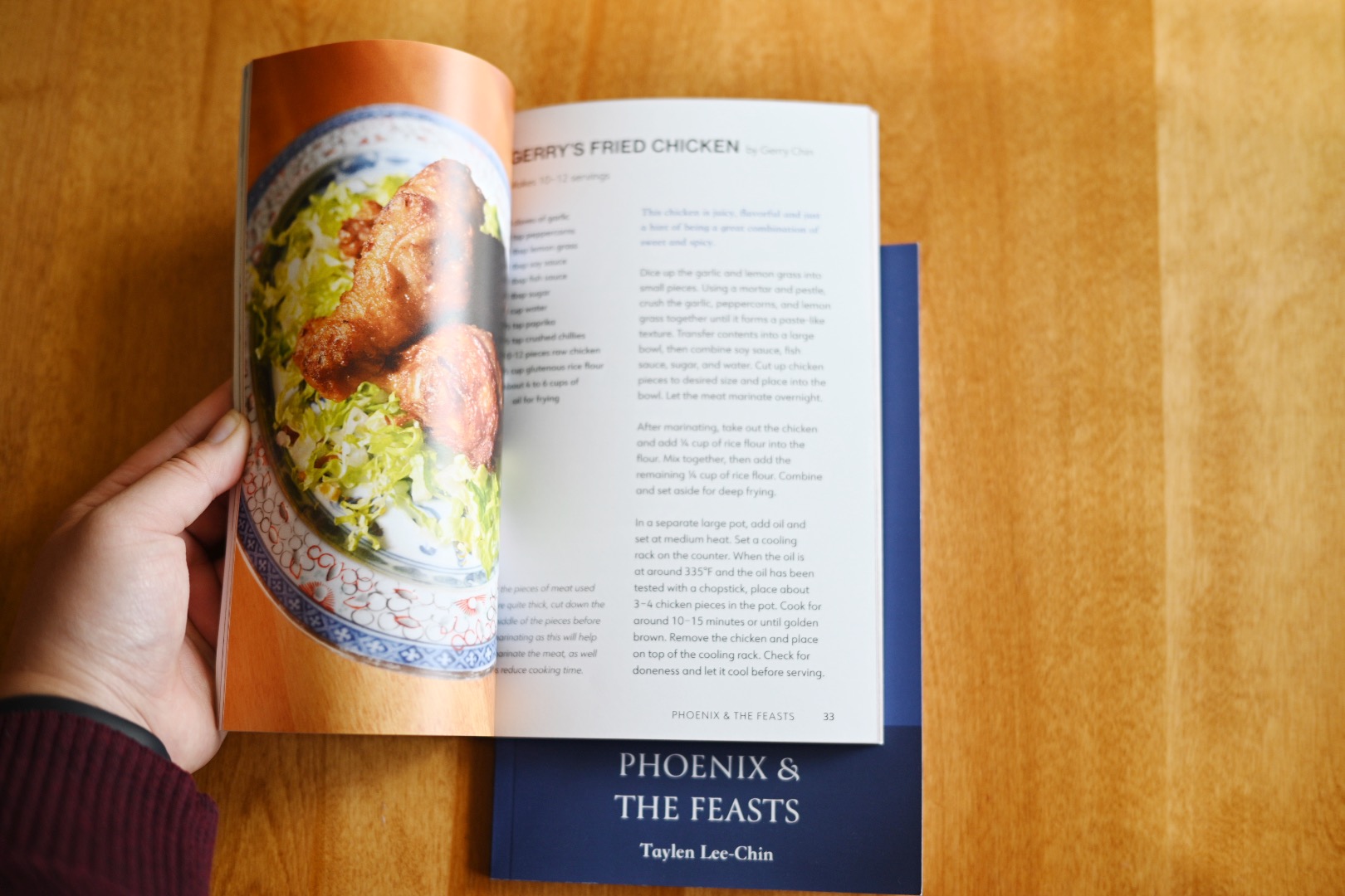 A hand opening the book to display a spread showcasing one of the recipes.